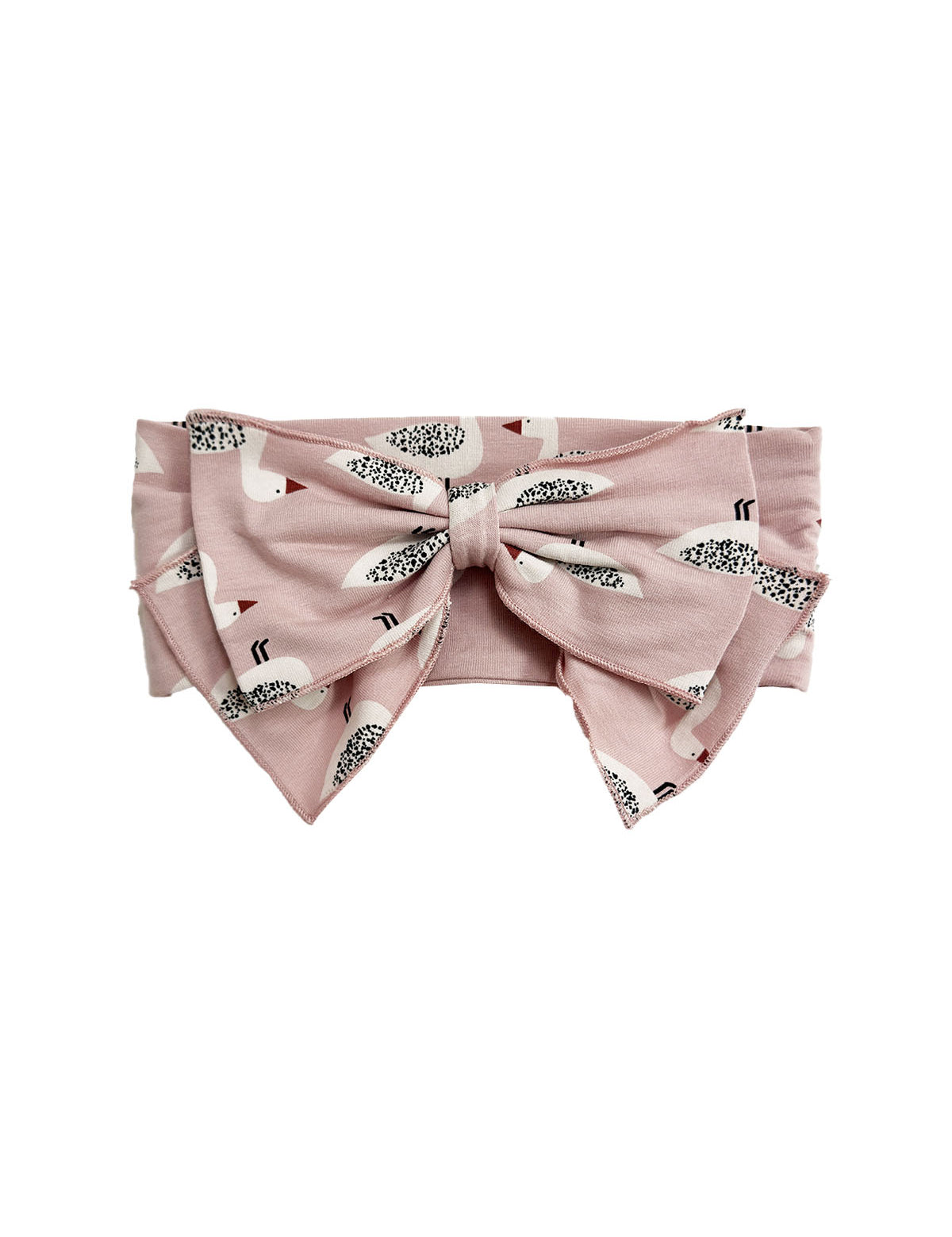 The Ducky in Pink Hair Accessory by Mabel and Honey is a pink headband with an oversized bow, decorated with a playful pattern of small white birds featuring black and brown details.