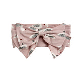The Ducky in Pink Hair Accessory by Mabel and Honey is a pink headband with an oversized bow, decorated with a playful pattern of small white birds featuring black and brown details.