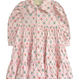 The Dixie Pink Floral Dress by Mabel and Honey is a long-sleeved dress with a tiered silhouette, pink floral pattern, a collar, and front buttons, shown flat on a white background.