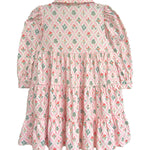 The Dixie Pink Floral Dress by Mabel and Honey features a vintage-inspired tiered silhouette with long sleeves, a collar, and gathered panels for a ruffled pink skirt accented with green and red floral designs.