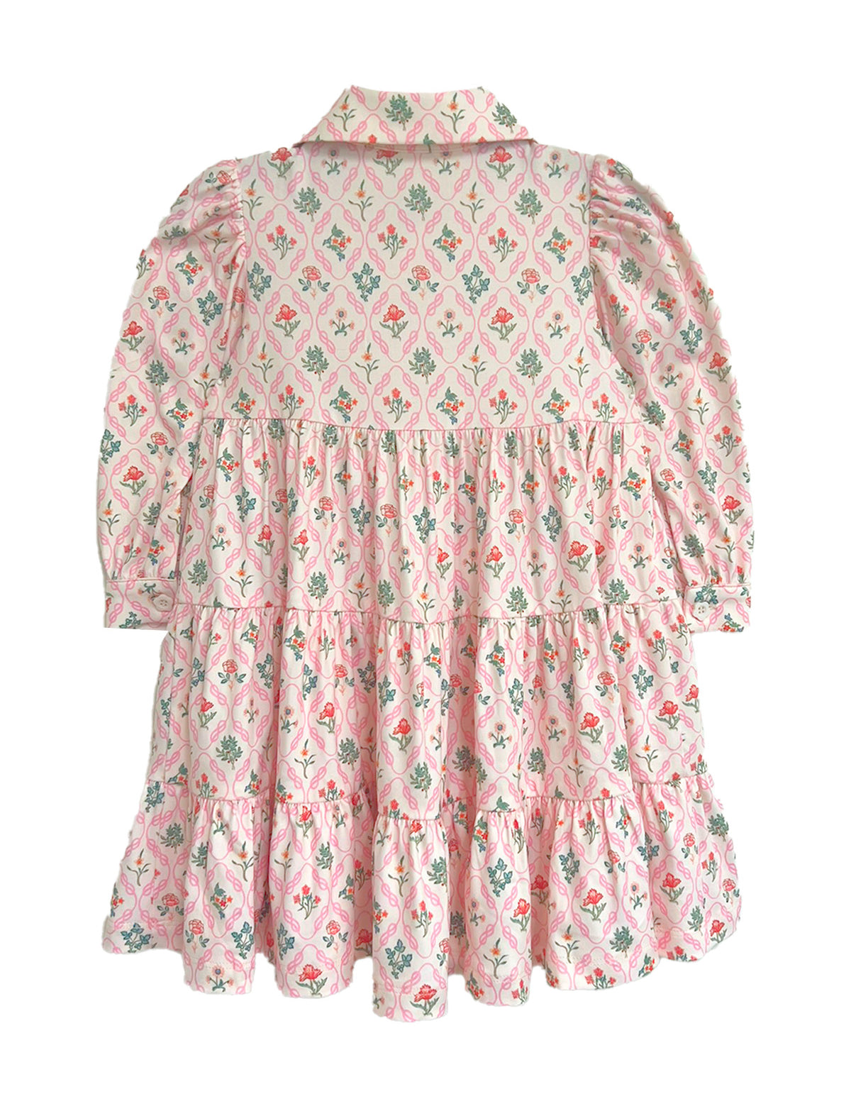 The Dixie Pink Floral Dress by Mabel and Honey features a vintage-inspired tiered silhouette with long sleeves, a collar, and gathered panels for a ruffled pink skirt accented with green and red floral designs.