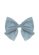 The Mabel and Honey Eva Hair Accessory is a large, light blue bow with a subtle floral pattern and gently curved ribbon tails, shown on a white background.