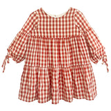 The Tis' the Season Dress by Mabel and Honey is a loose-fitting, long sleeve red and white gingham dress with tiered ruffles and cuff bow ties—ideal as a holiday dress for girls.