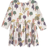 The Mabel and Honey Treehouse Dress is long-sleeved with a gathered waist, showcasing whimsical trees in muted green, purple, pink, and yellow on a light background. A keyhole button at the back adds a charming, nature-inspired touch.