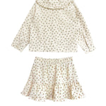 The Juliette Two Piece Set by Mabel and Honey is a charming girls’ outfit featuring an off-white long-sleeve top with ruffle collar and a matching floral ruffle skirt.