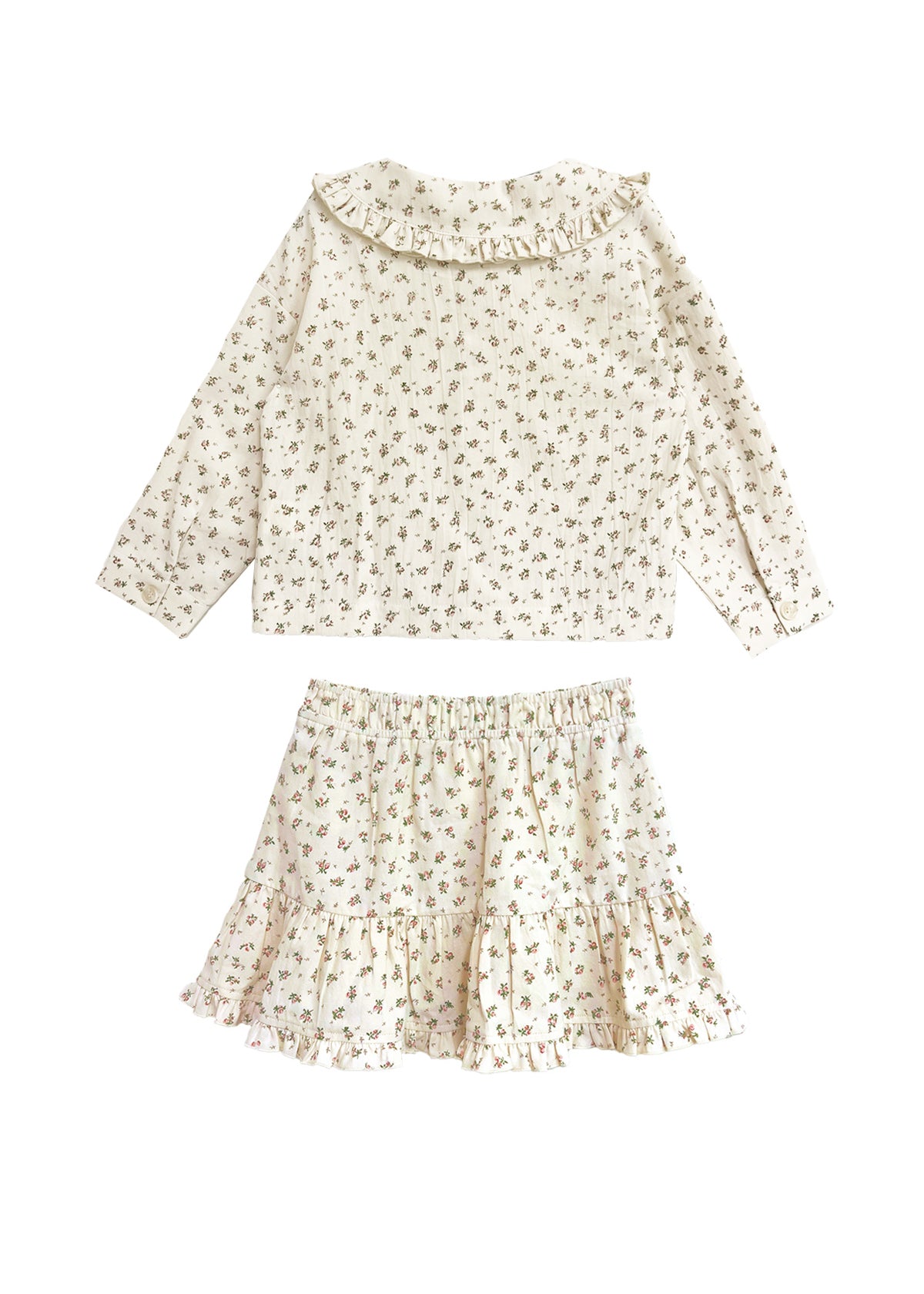 The Juliette Two Piece Set by Mabel and Honey is a charming girls’ outfit featuring an off-white long-sleeve top with ruffle collar and a matching floral ruffle skirt.