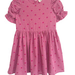 The Mabel and Honey Perfect in Pink Hearts Short Sleeve Dress is a girls’ pink dress with puffed ruffled sleeves, a flared skirt, and a sweet pattern of small, darker pink hearts.