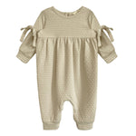 The Cinnamon Sugar Romper by Mabel and Honey is a beige textured baby girl's romper with long sleeves, gathered waist, sleeve bows, and a footless design—perfect for cozy everyday comfort.