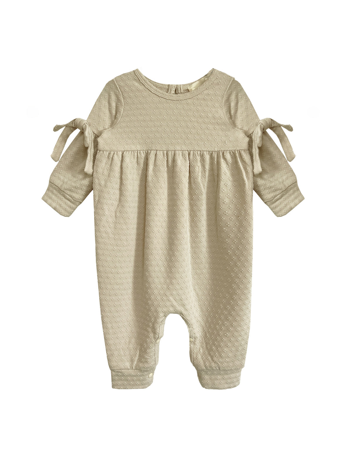 The Cinnamon Sugar Romper by Mabel and Honey is a beige textured baby girl's romper with long sleeves, gathered waist, sleeve bows, and a footless design—perfect for cozy everyday comfort.