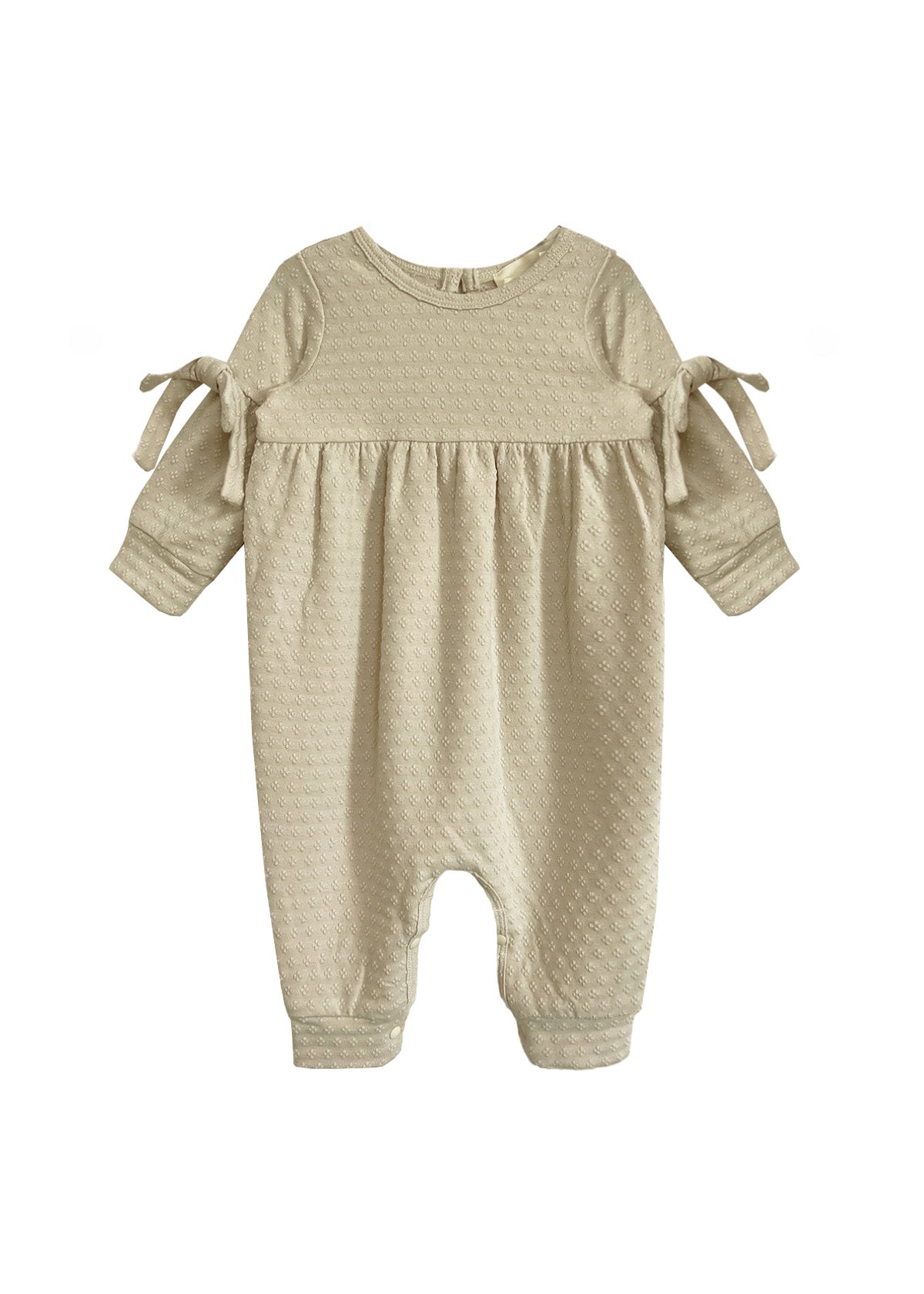 The Cinnamon Sugar Romper by Mabel and Honey is a beige textured baby girl's romper with long sleeves, gathered waist, sleeve bows, and a footless design—perfect for cozy everyday comfort.