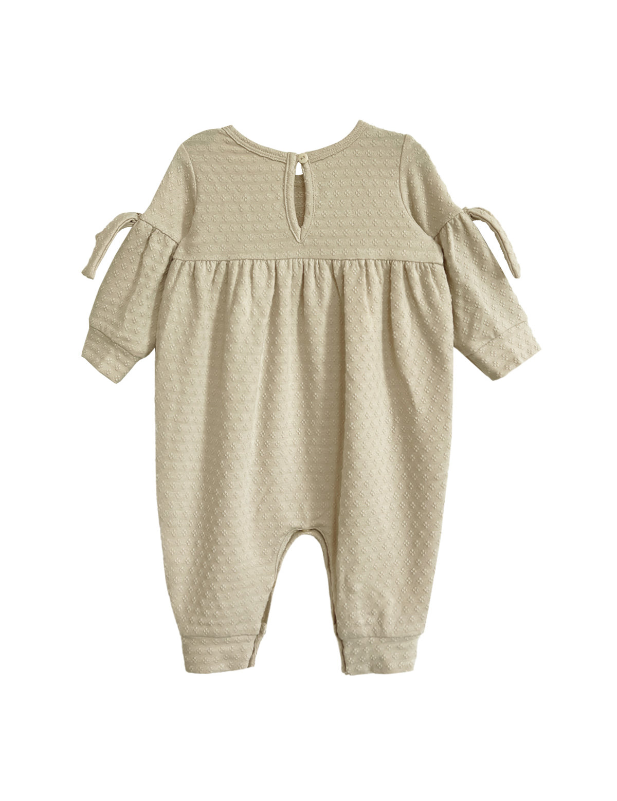 The Cinnamon Sugar Romper by Mabel and Honey is a beige, long-sleeve baby girl romper with textured fabric, a gathered waist, bow-tied sleeves, back button closure, and cuffed ankles for a sweet and comfy fit.