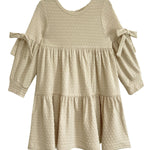 The Mabel and Honey Cinnamon Sugar Dress is a cream-colored toddler dress with textured fabric, a tiered silhouette, long sleeves, and decorative bows on each sleeve.