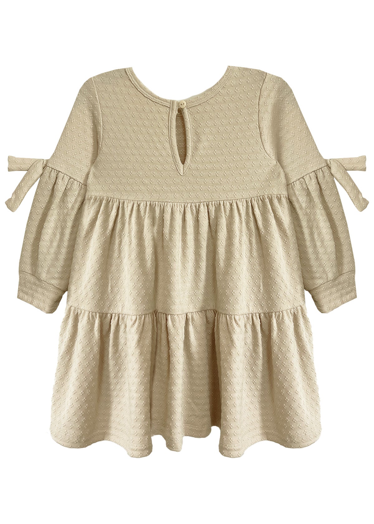 The Cinnamon Sugar Dress by Mabel and Honey features a cream, long-sleeve tiered design with textured dot fabric, ruffled skirt, small bow ties on the arms, and a keyhole button closure at the back for easy dressing.
