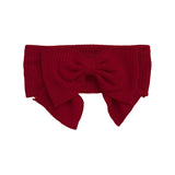 The Rosie Hair Accessory by Mabel and Honey is a bold red, ribbed headband with a large bow in the center for an eye-catching style.