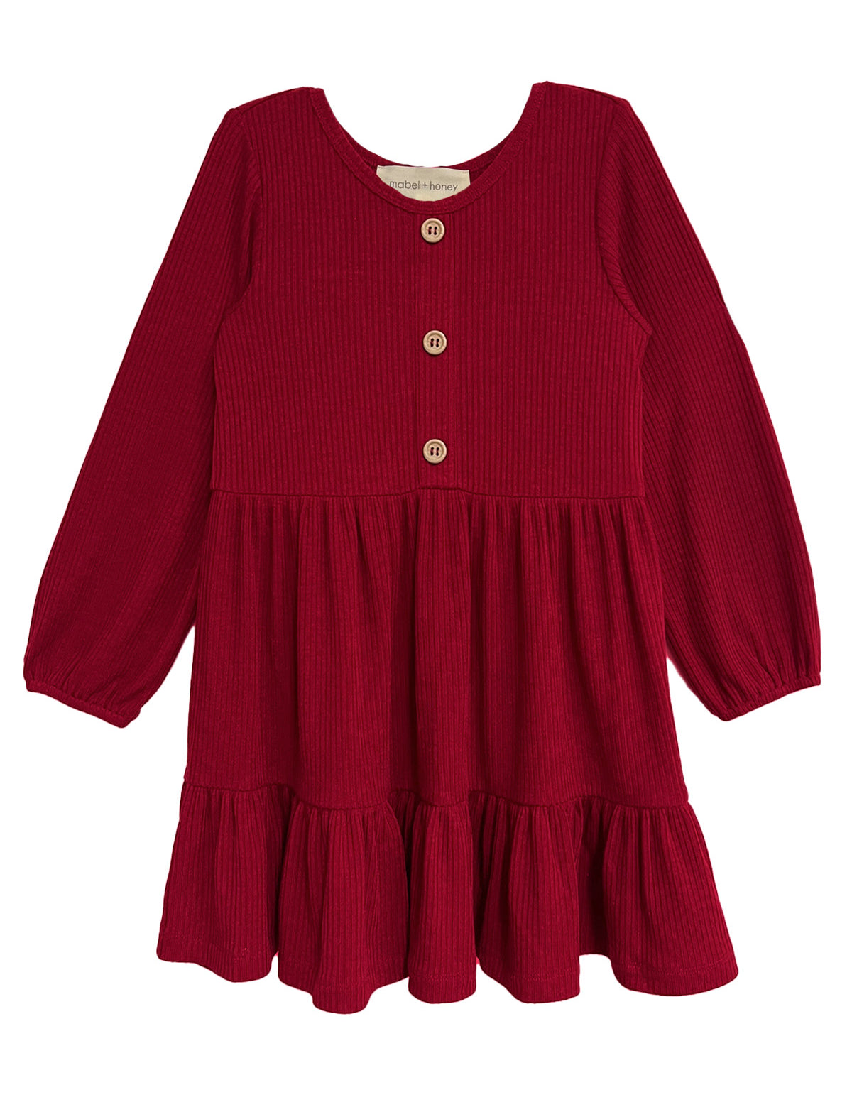 The Mabel and Honey Rosie Dress is a red, long-sleeve girl’s dress with ribbed fabric, wooden front buttons, a round neckline, and a gathered ruffled skirt.