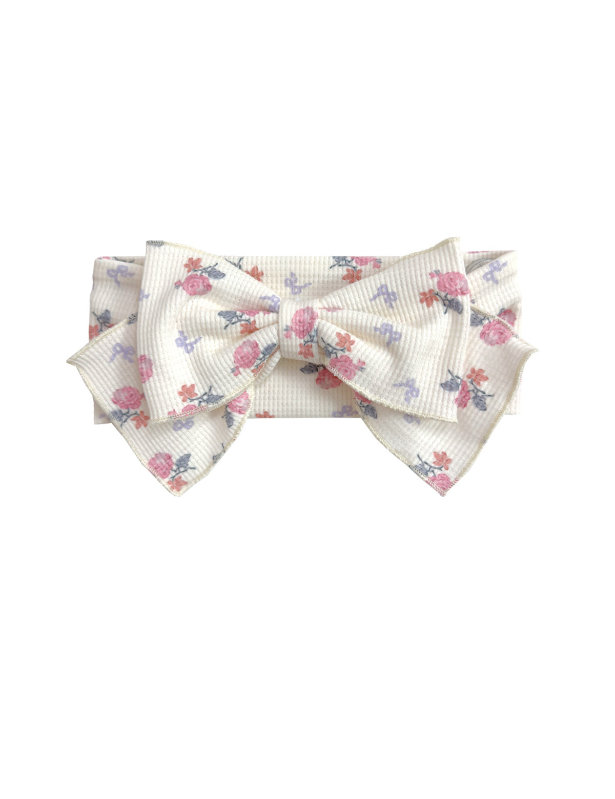 The Mia Hair Accessory by Mabel and Honey is an ivory ribbed fabric headband with a large bow, adorned with a pink and purple floral design.