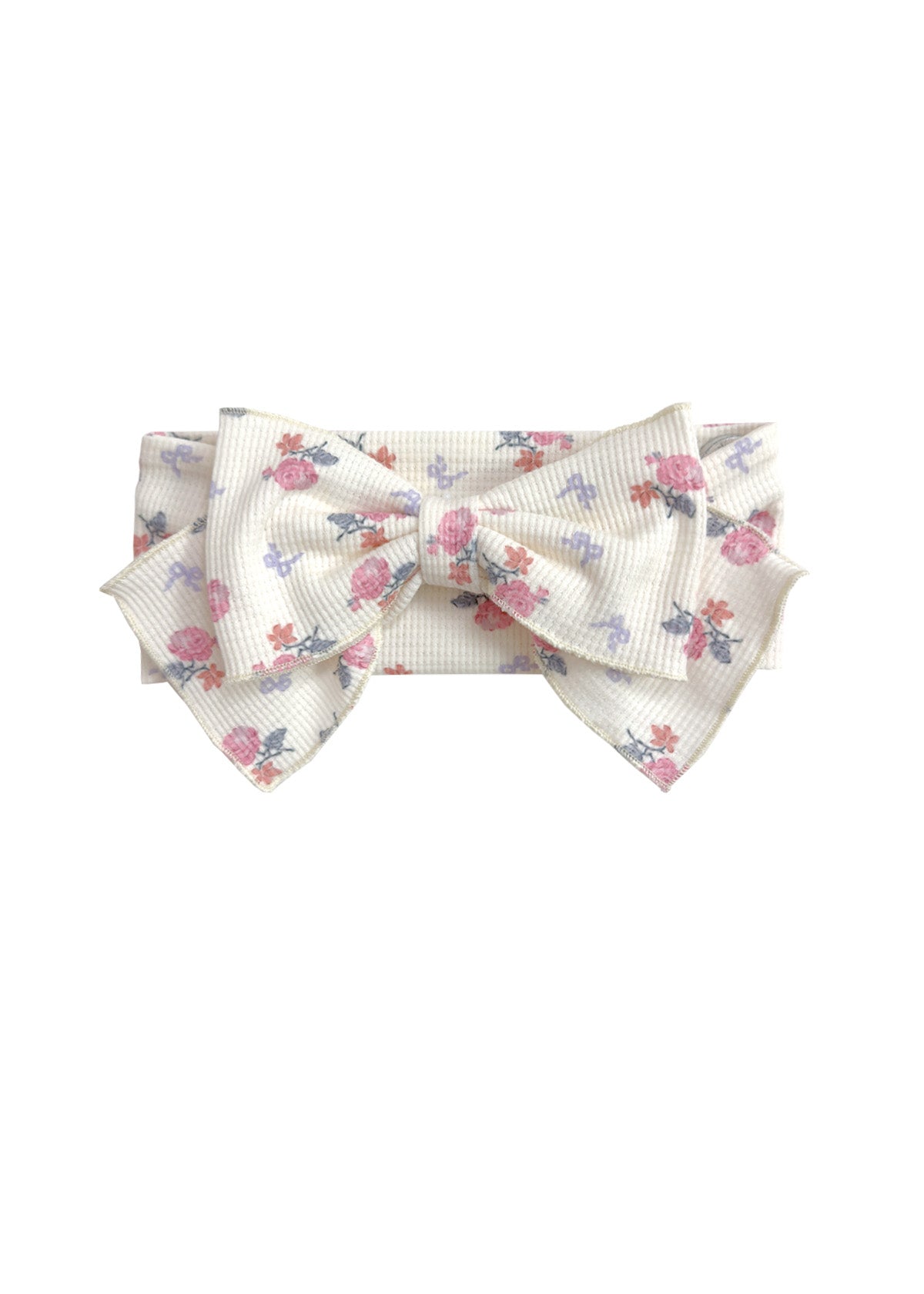The Mia Hair Accessory by Mabel and Honey is an ivory ribbed fabric headband with a large bow, adorned with a pink and purple floral design.