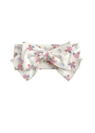 The Mia Hair Accessory by Mabel and Honey is an ivory ribbed fabric headband with a large bow, adorned with a pink and purple floral design.