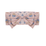The Lavender Mae Hair Accessory by Mabel and Honey showcases a large pink bow in soft fabric, detailed with a blue and green floral pattern.