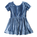 The Isobella and Chloe Starry Blue Velvet Dress features short sleeves, a round neckline, and a gathered flared skirt, making it perfect for girls’ special occasions. Shown in knee-length on a plain white background.