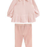 The Serena Two Piece Set by Mabel and Honey is a light pink girls’ outfit with a long-sleeve, collared top featuring a pleated hem and matching elastic-waist pants, both crafted from soft fabric.