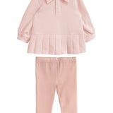 The Serena Two Piece Set by Mabel and Honey is a light pink girls’ outfit with a long-sleeve, collared top featuring a pleated hem and matching elastic-waist pants, both crafted from soft fabric.