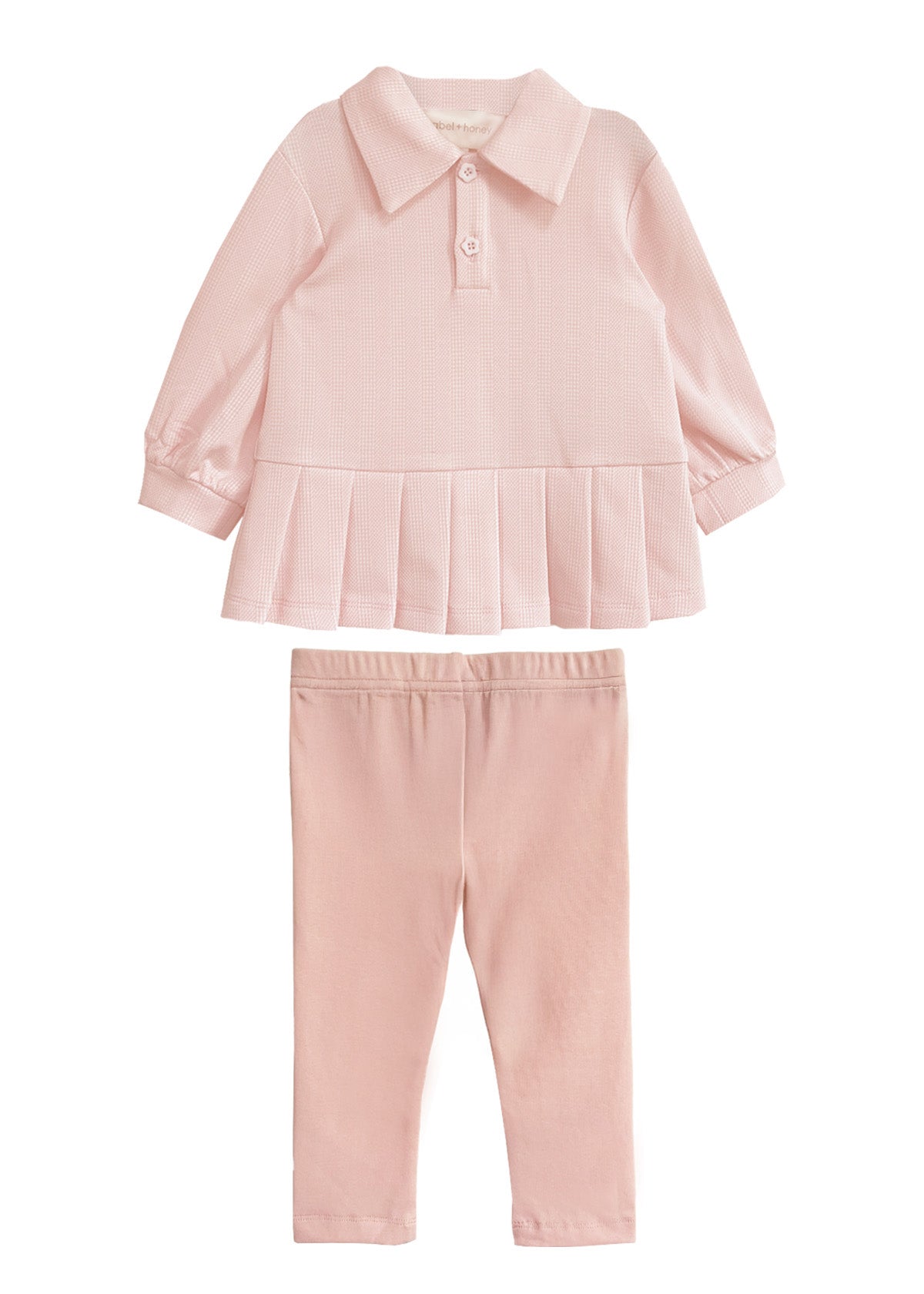 The Serena Two Piece Set by Mabel and Honey is a light pink girls’ outfit with a long-sleeve, collared top featuring a pleated hem and matching elastic-waist pants, both crafted from soft fabric.