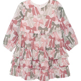 The Bow-tiful Dress by Mabel and Honey is a girls’ long sleeve dress with playful tiers, ruffles, and a pink-and-green bow print on crisp white.