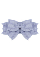 The Lena Hair Accessory by Mabel and Honey features a light lavender hue, a large ruched bow at the center, and a textured elastic band for stylish comfort.