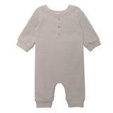The Isaac Romper by Beckett and Bear showcases a light gray, neutral design with ribbed cuffs, a round neckline, three wooden chest buttons, and leg snap closures. The soft fabric ensures comfort for your baby.