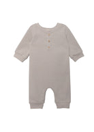 The Isaac Romper by Beckett and Bear showcases a light gray, neutral design with ribbed cuffs, a round neckline, three wooden chest buttons, and leg snap closures. The soft fabric ensures comfort for your baby.