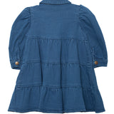 The Denim Days Tiered Dress by Mabel and Honey is a girls’ long-sleeved blue denim dress with a collar, buttoned cuffs, and a flared tiered skirt, shown flat with the back side facing up.