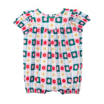 The Mabel and Honey Flower Pops Short Sleeve Romper features a colorful checkered pattern with red, yellow, and white flowers on teal and light blue squares, plus gathered sleeve and leg cuffs for a cute baby girl look.