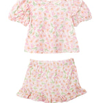The Wild Savanna Short Gathered Sleeve Two Piece Set by Mabel and Honey features a pink, yellow, and green floral print with a ruffled short-sleeve top and matching elastic-waist shorts with ruffled hems.