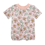 The Quinn Short Sleeve Romper by Mabel and Honey features a light pink background with yellow and pink flowers, green leaves, a pink collar, and elastic leg openings for comfort. Breathable and perfect for your baby.