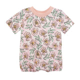 The Quinn Short Sleeve Romper by Mabel and Honey features a light pink background with yellow and pink flowers, green leaves, a pink collar, and elastic leg openings for comfort. Breathable and perfect for your baby.