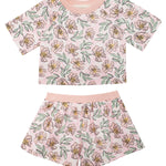 The Quinn Short Sleeve Two Piece Set by Mabel and Honey features a pink floral cropped top and shorts with yellow and green accents—an airy, stylish outfit for girls, perfect for summer nights.