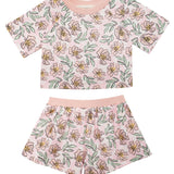 The Quinn Short Sleeve Two Piece Set by Mabel and Honey features a pink floral cropped top and shorts with yellow and green accents—an airy, stylish outfit for girls, perfect for summer nights.