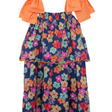 The Fiesta Cap Sleeve Dress by Mabel and Honey features bold orange bow straps, a navy blue base with colorful floral prints, and a scalloped hem. Its tiered, flowy design ensures comfortable wear for any day.