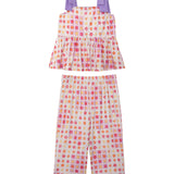 The Mabel and Honey Petal Power Tank Sleeve with Knot Detail Two Piece Set features a sleeveless peplum top with purple bows and wide-leg pants, both in a vibrant pink, orange, and purple geometric floral print on cream.
