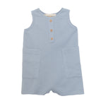 The Rowland Sleeveless Romper by Beckett and Bear features a light blue waffle knit, three wooden buttons, and two large front pockets for toddlers, shown on a white background.
