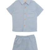 The Beckett and Bear Rowland Short Sleeve Two Piece Set features a light blue checkered shirt with brown buttons and chest pocket, plus matching shorts. Both pieces are laid flat on a white background.