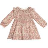 The Autumn Floral Tan Long Sleeve Dress by Mabel + Honey features a red floral pattern, smocked front bodice, ruffled shoulders, flared skirt, and elastic cuffs for comfort. Perfect for toddlers.