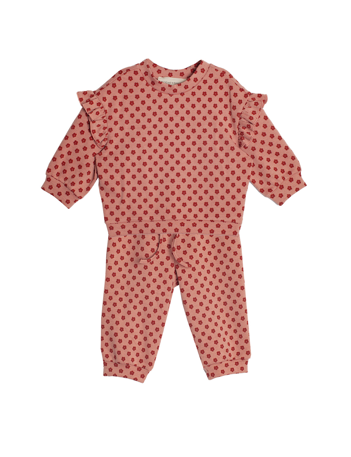 The Red Velvet Two Piece Set by Mabel and Honey is a soft knit toddler outfit with a long-sleeve ruffled top and matching pink pants decorated with red polka dots.