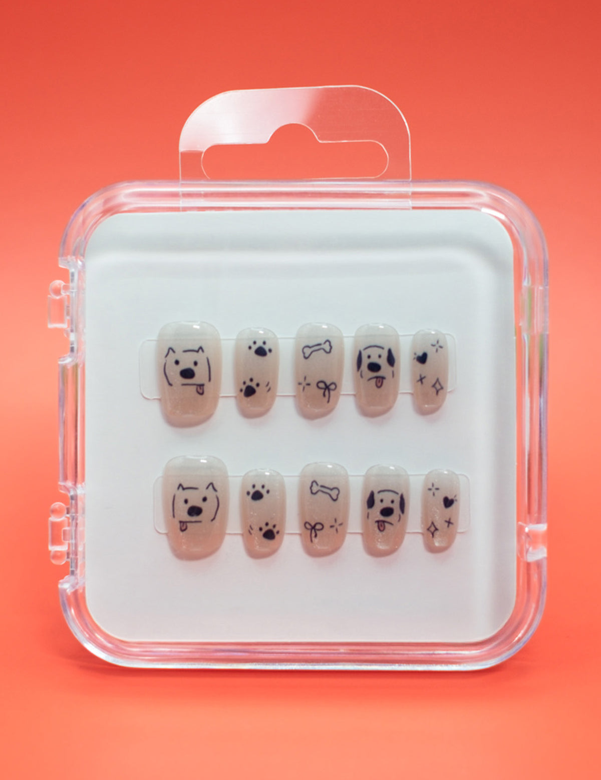 Paw-fection by Mabel and Honey: salon-quality press-on nails in a clear case, each with black dog faces, bones, paw prints, and stars on a nude background—all set against an orange backdrop.