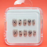 Paw-fection by Mabel and Honey: salon-quality press-on nails in a clear case, each with black dog faces, bones, paw prints, and stars on a nude background—all set against an orange backdrop.