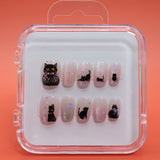 Cat Blossom by Mabel and Honey offers reusable press-on nails in a clear case, each nail featuring black cat designs with floral accents—perfect for achieving a salon-quality manicure at home.