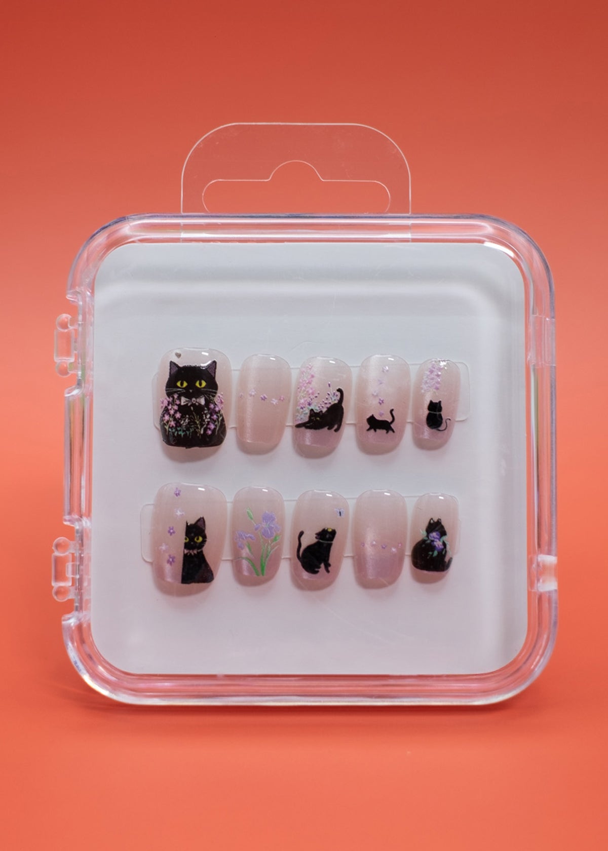 Cat Blossom by Mabel and Honey offers reusable press-on nails in a clear case, each nail featuring black cat designs with floral accents—perfect for achieving a salon-quality manicure at home.