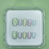 Mabel and Honey’s Confetti set features pastel green, purple, and blue salon-quality press-on nails with iridescent holographic accents, displayed in a clear case against a matching green background.