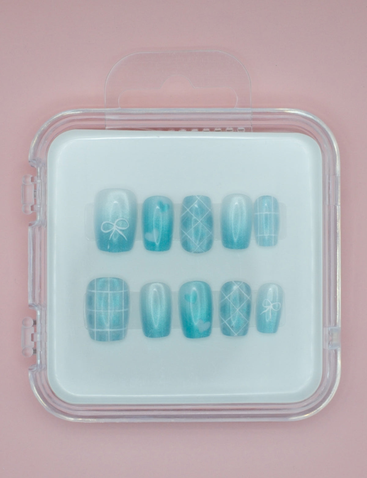 Ice Princess by Mabel and Honey: blue salon-quality press-on nails with white bows and grid designs, displayed in a clear case against a pink background.